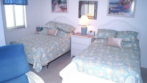Un dormitorio con dos camas, una mesita de noche, una lámpara y una silla.