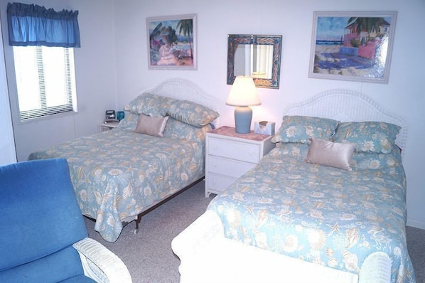 Une chambre avec deux lits, une table de chevet, une lampe et une chaise.