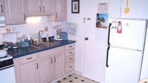 Una cocina compacta con armarios de madera clara, un refrigerador blanco y una encimera azul.