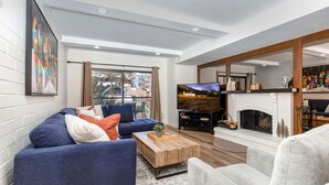 Una sala de estar moderna con un sofá azul, una mesa de centro, una chimenea y un televisor.