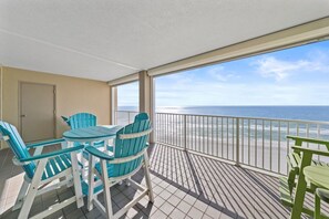 Ein Balkon mit Blick auf Strand und Meer, ausgestattet mit Tisch und Stühlen.