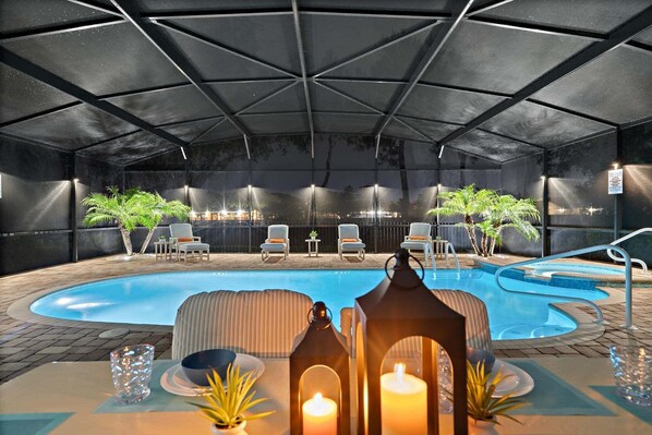 An indoor pool area with lounge chairs, a pool table, and candles.