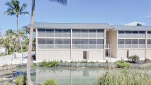 Un edificio moderno con techo plano, múltiples ventanas y una pequeña piscina al frente.