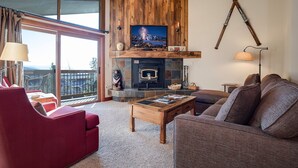 A cozy living room with a fireplace, a large window, and a view of the mountains. - RA204 | Excellent Amenities | Pool | Hot Tub | Winter Shuttle | Great Views (Steamboat Springs)