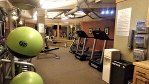 Un gimnasio con equipamiento de ejercicio, una cinta de correr y una bicicleta estática.