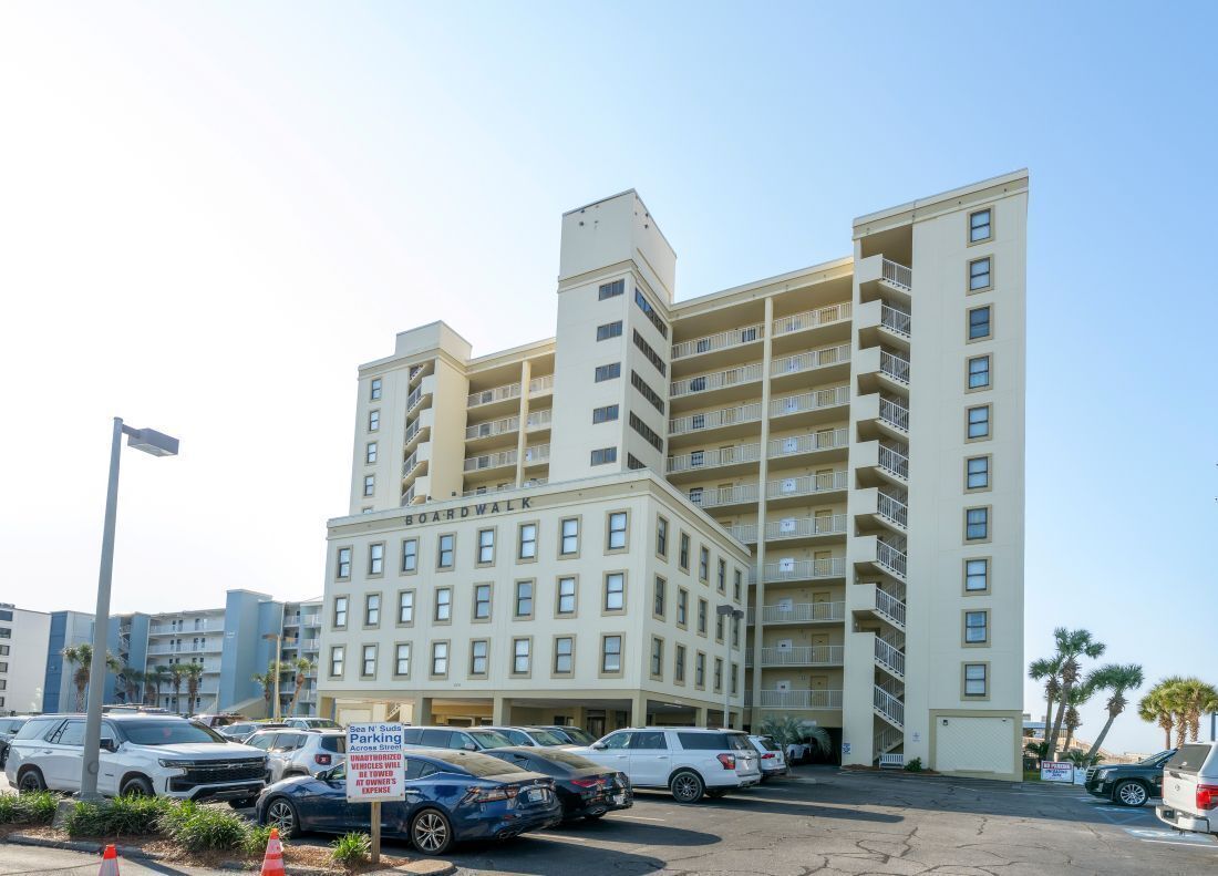 A multi-story hotel with a parking lot in front.