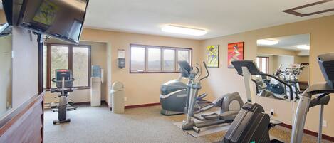 A gym with treadmills, elliptical machines, and a water dispenser.