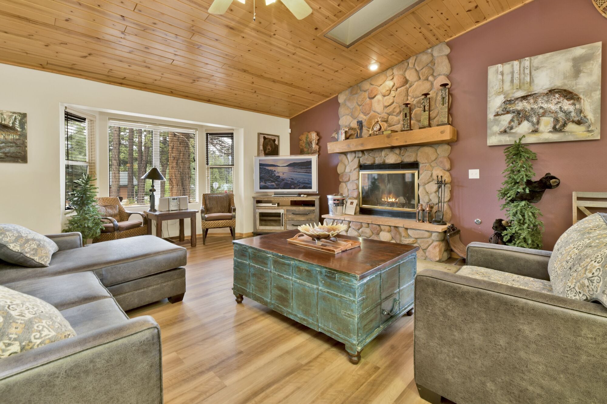 Cozy mountain living room with wood ceilings, stone fireplace, comfy seating, and smart TV—perfect for relaxing evenings, movie nights, and warm cabin vibes after outdoor adventures.