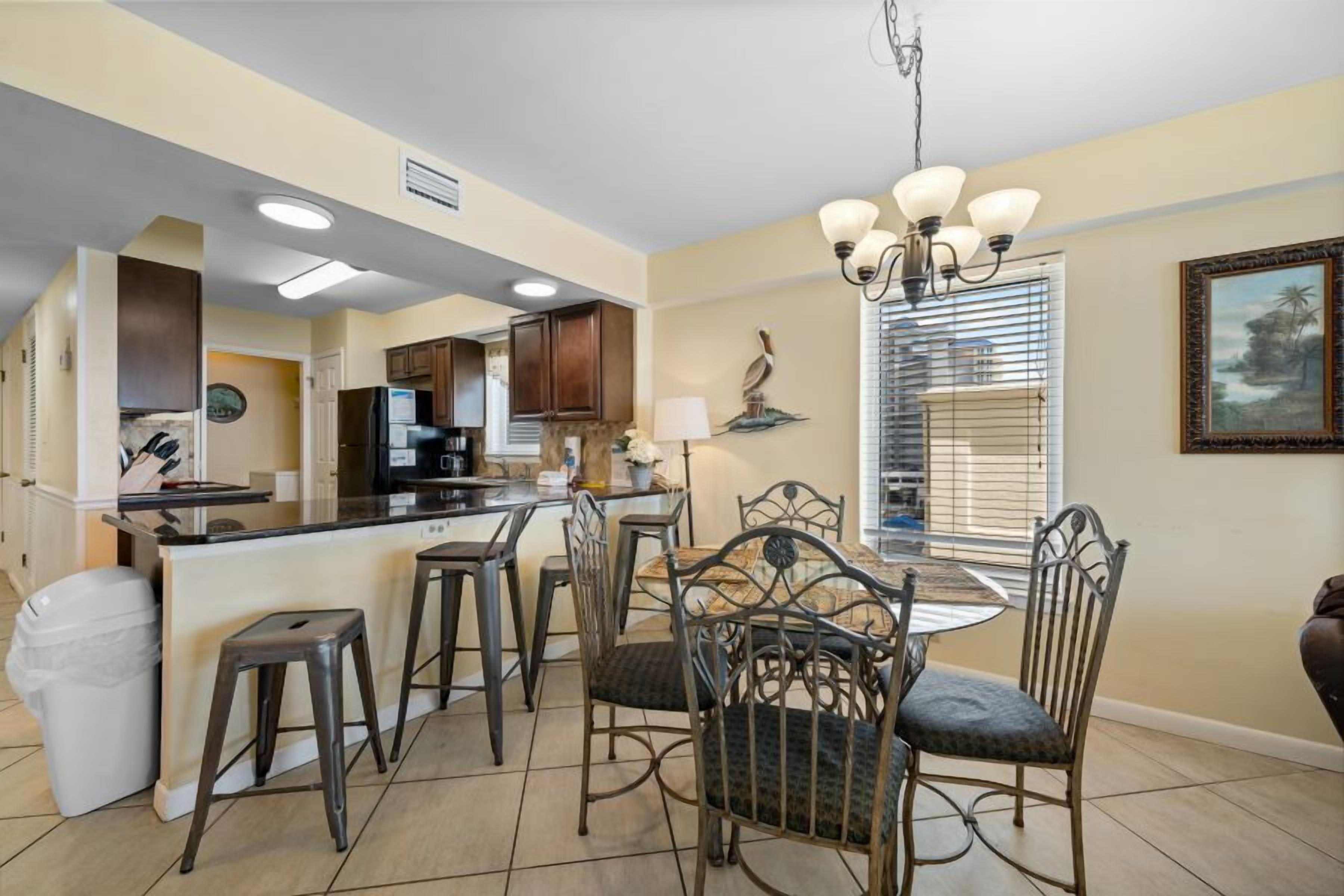 Cozinha com bancada, mesa de jantar e cadeiras, e um candelabro.