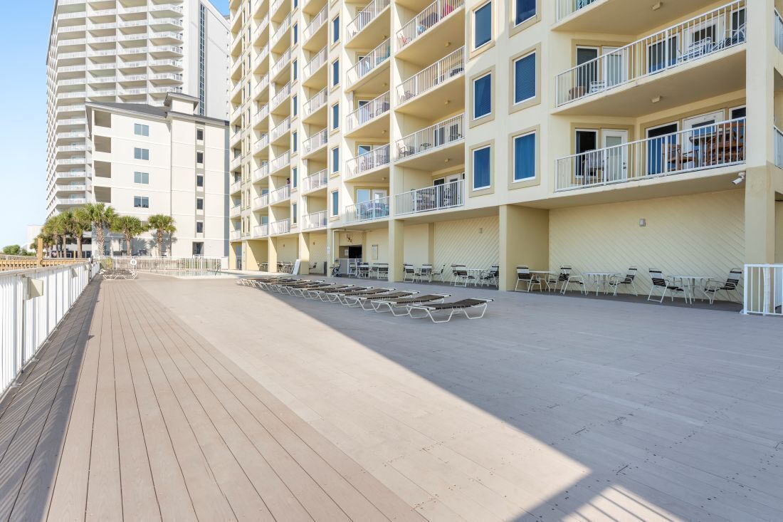 A multi-story hotel with balconies, a wooden deck, and outdoor seating.