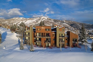 A modern multi-story hotel with a wooden facade, located in a snowy mountainous area. - W3321 | Gorgeous Updated Condo | Pool | Walk to Mtn Village | Winter Shuttle (Steamboat Springs)
