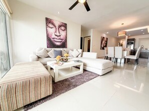 A modern living room with a sofa, coffee table, and a dining area with chairs.