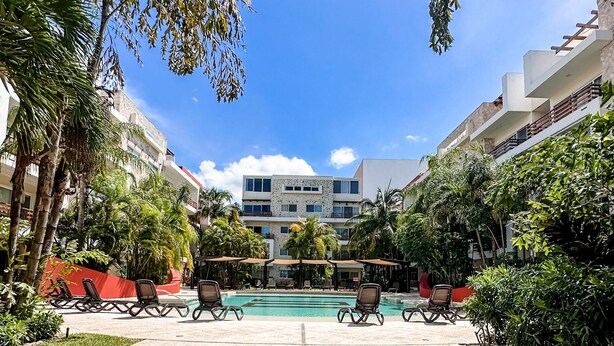 A pool area with lounge chairs, a water feature, and a building in the background.