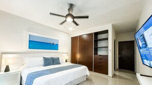 A modern bedroom with a bed, a ceiling fan, a wardrobe, and a TV.