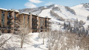 A multi-story hotel with balconies, set against a snowy mountain backdrop. - CA315 | Ski In/Out | W/D | Winter Shuttle | Ski In/Out | Pool | Hot Tub (Steamboat Springs)