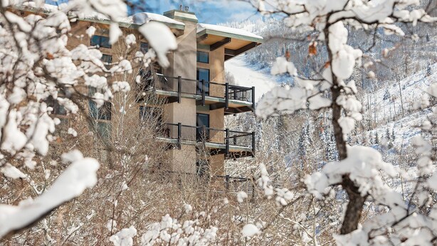 A modern building with a balcony, surrounded by snow-covered trees. - CA315 | Ski In/Out | W/D | Winter Shuttle | Ski In/Out | Pool | Hot Tub (Steamboat Springs)