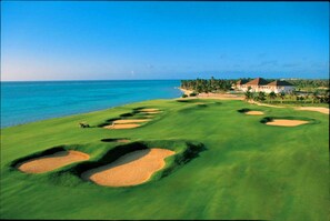 Een golfbaan met bunkers en uitzicht op de oceaan.