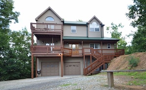 Ein zweistöckiges Haus mit Veranda, überdachter Auffahrt und Treppe zum Obergeschoss.