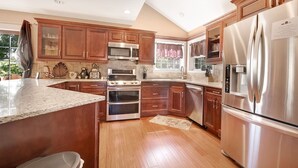 A modern kitchen with wooden cabinets, stainless steel appliances, and a granite countertop. - Fontana View Retreat - Free Whitewater Rafting Passes + Luxury Family Home w/ (Fontana Dam)