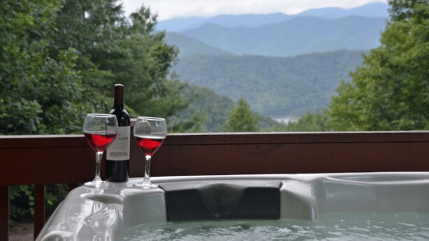 A hot tub with two glasses of red wine and a bottle on a wooden deck overlooking a mountainous landscape. - Fontana View Retreat - Free Whitewater Rafting Passes + Luxury Family Home w/ (Fontana Dam)