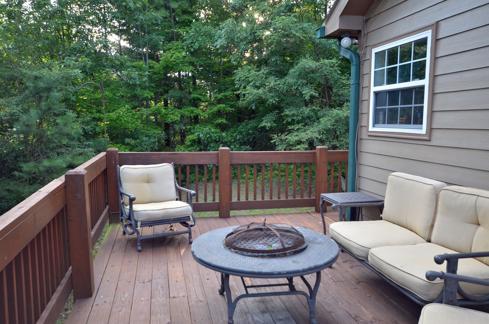 A wooden deck with a sofa, two chairs, and a table.