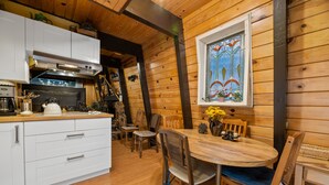 Un interior de madera con cocina, comedor y un ventanal de vidrio emplomado.