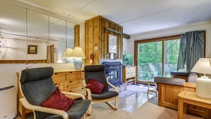 Une pièce comprenant deux fauteuils, un bureau en bois, une lampe et une vue sur la verdure par une fenêtre.
