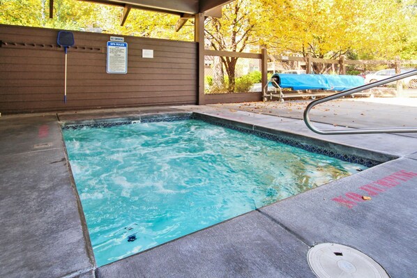 A hot tub with a wooden deck and a 'No Smoking' sign.