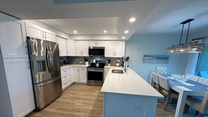 A modern kitchen with white cabinetry, stainless steel appliances, and a central island. - TRENDY BEACH CONDO ON THE GROUND FLOOR! (Sanibel)