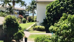 A residential area with a white building, palm trees, and a well-maintained lawn. - TRENDY BEACH CONDO ON THE GROUND FLOOR! (Sanibel)
