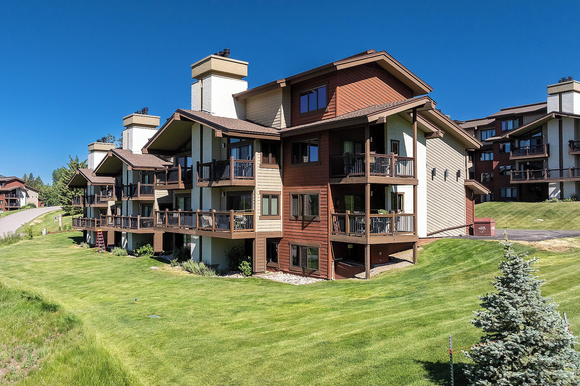 A multi-story hotel with balconies, a well-maintained lawn, and a clear sky.