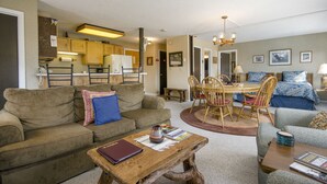 A cozy living room with a sofa, a coffee table, and a dining area with chairs and a table.