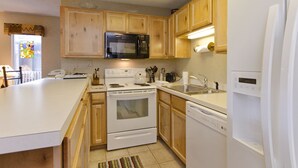 A kitchen with wooden cabinets, a microwave, a stove, a dishwasher, and a refrigerator.