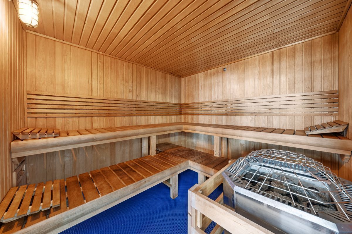 En sauna med træbænke og et metalvarmeanlæg.