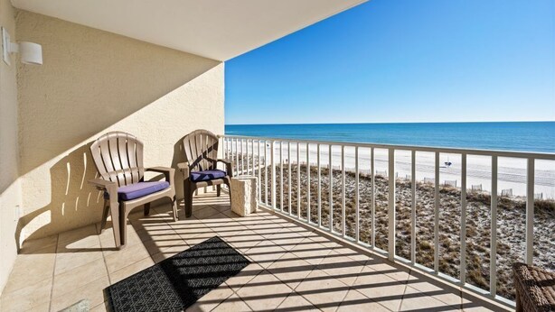 Un balcone con due poltrone Adirondack, un tavolino e vista sulla spiaggia.
