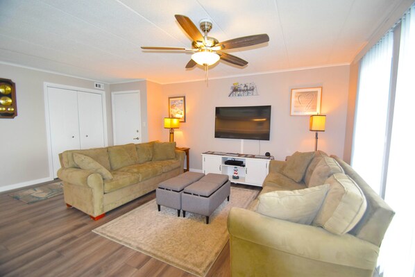 A living room with two sofas, a coffee table, a TV, and a ceiling fan. - Thunder Island 61B-Baywater 39th St, Free WiFi, Pool, Elev, W/D, AC (Ocean City)