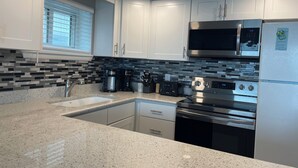 A modern kitchen with white cabinets, a granite countertop, a stainless steel oven, a microwave, and a coffee maker. - Thunder Island 61B-Baywater 39th St, Free WiFi, Pool, Elev, W/D, AC (Ocean City)