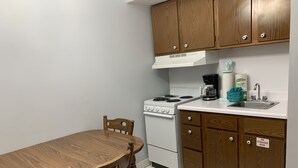 A kitchen with wooden cabinets, a white stove, a coffee maker, and a sink. - Oak Square 109 is a spacious condo with private balcony in downtown (Gatlinburg)
