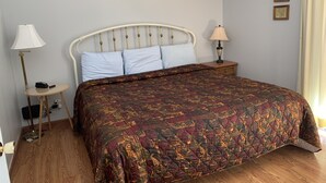 A neatly made bed with a patterned bedspread, a bedside lamp, a small table with a lamp, and two framed maps on the wall. - Oak Square 109 is a spacious condo with private balcony in downtown (Gatlinburg)