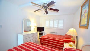 A bedroom with two beds, a ceiling fan, a TV, a dresser, and a window with blinds.