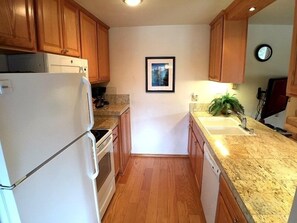 Kitchen area with a refrigerator, sink, and wooden cabinets.