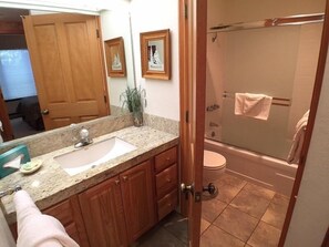 Bathroom features a glass-enclosed shower, toilet, and wooden cabinets.