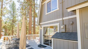 A wooden deck with outdoor furniture, a covered seating area, and a view of a forested area.