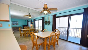 Un espace repas comprenant une table et des chaises, un ventilateur de plafond et de grandes fenêtres.