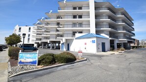 Un hôtel à plusieurs étages, avec un toit bleu, une enseigne indiquant « 110, rue 81 » et un parking situé devant.
