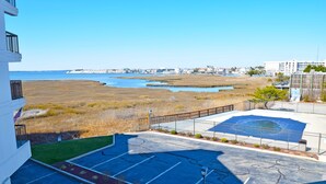 Vue depuis un balcon donnant sur une plage, avec un espace de stationnement et un terrain de basketball.