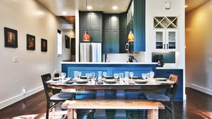 A modern kitchen with dark blue cabinets, a stainless steel refrigerator, and pendant lighting.