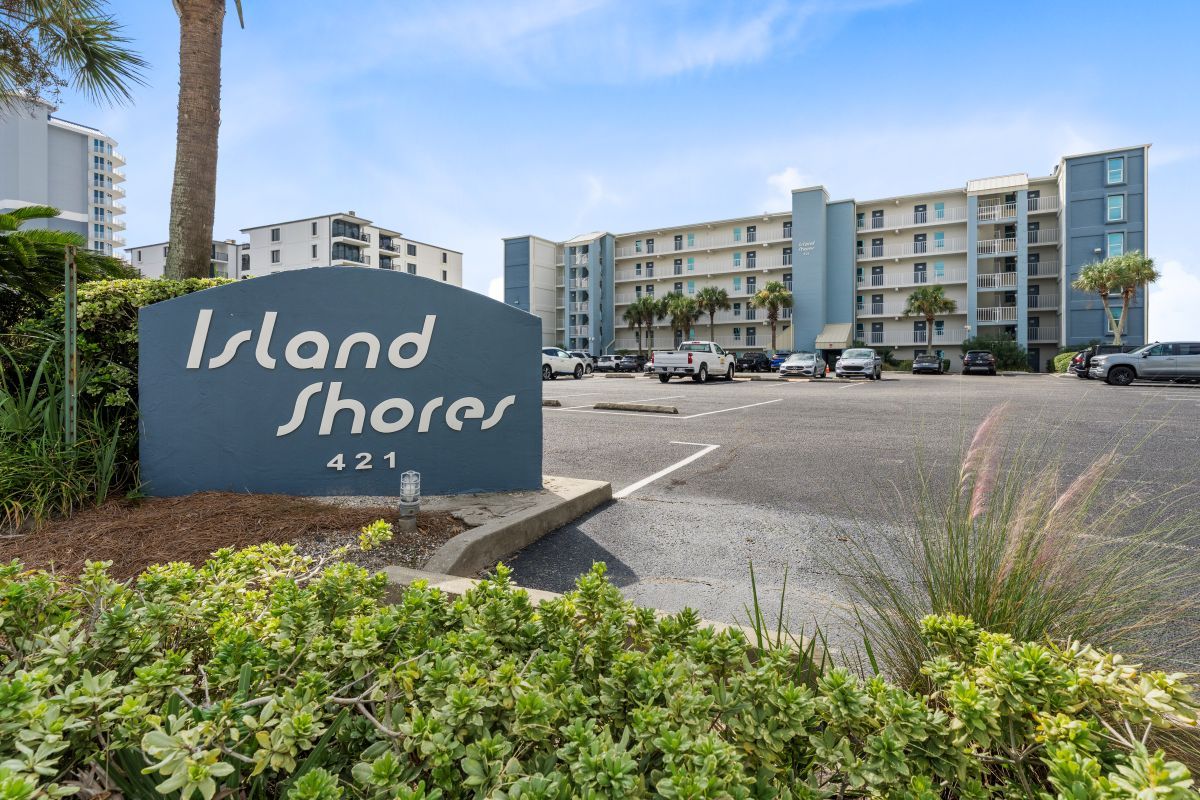 A sign for 'Island Shores' with a parking lot in the foreground.