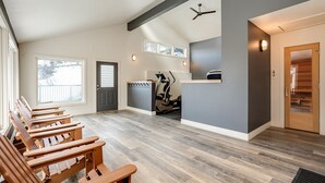 A spacious room with a long wooden bench, a ceiling fan, and a treadmill.