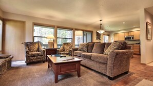 A living room with a sofa, two armchairs, a coffee table, and a lamp. There is a kitchen area visible in the background. - The Ridge at Sunriver - Condo #45 - Access provided to onsite seasonal swimming pool & tennis facilities, year-round hot tub plus 4 bikes (Sunriver)